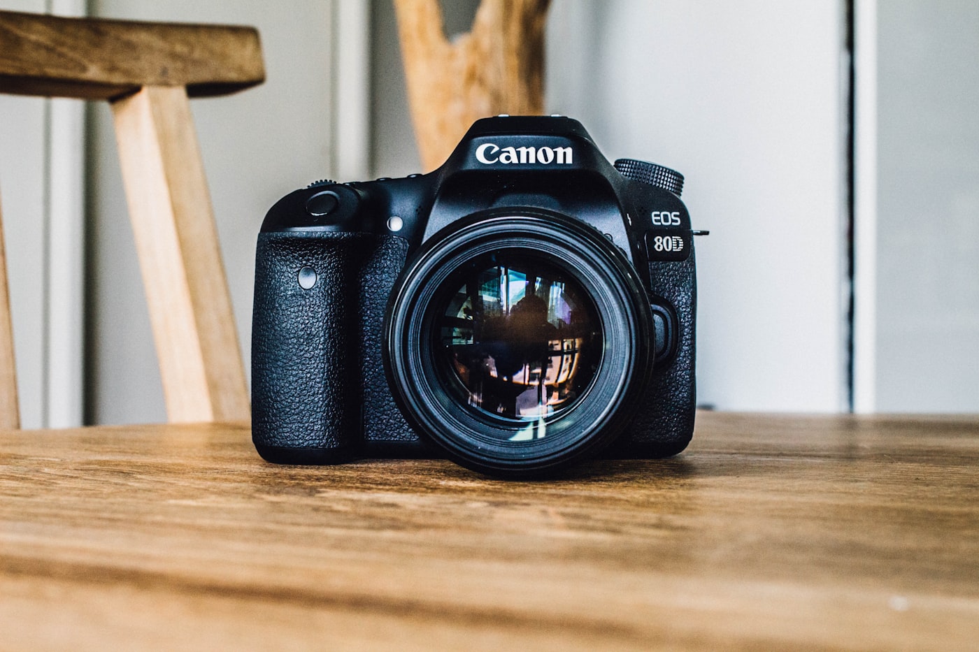 A Canon DSLR resting on a warm wooden table in soft daylight